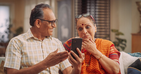 Amazing Elderly Indian Couple Using Smartphone for Video Call at Home. Beautiful Hindu Granparents Waving and Greeting Grandchildren, Talking with Relatives and Friends. Medium Close-up 
