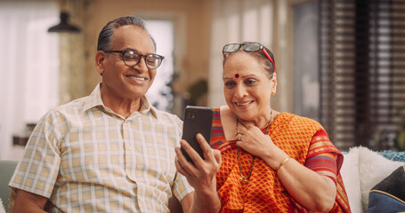 Elderly Couple Using Smartphone for Video Call at Home: Connecting with Family, Sharing Stories, and Celebrating Special Occasions. Cherishing Precious Moments Together. Medium Shot.