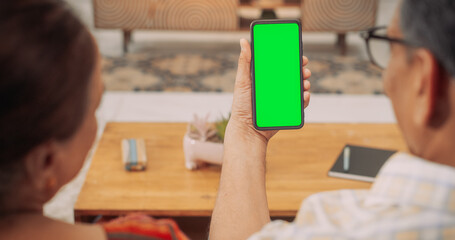 Over the Shoulder Elderly Indian Couple Using Smartphone with Green Screen: Exploring the Latest Mobile Software, Using Social Media and Sharing Fun Experiences. Enjoying Digital Online Shopping