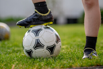 Obraz premium young boy standing on a ball on football field in the garden during football lesson