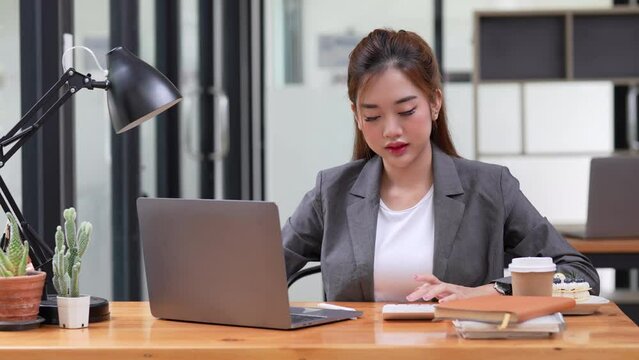 businesswoman working on desk office with using a calculator to calculate the numbers at office, finance accounting concept