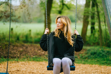 Joyful and youthful woman on a swing at the park. Concept pf people and no limit age to play and...