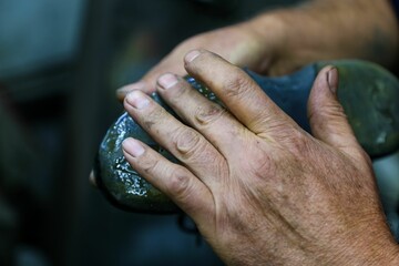 Closeup shot of the hand of a shoe maker preparing his working tools with blur background
