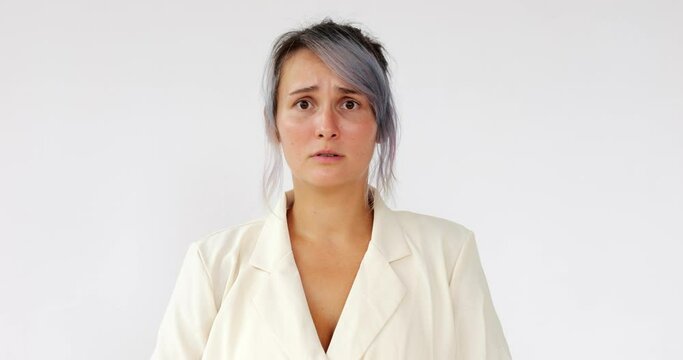 Attractive woman watches as something scary and little creepy happens, and fear and empathy appear on her face. Portrait of young woman with dyed hair, against white background