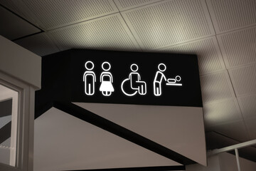 Symbols on black sign in mall near public toilet