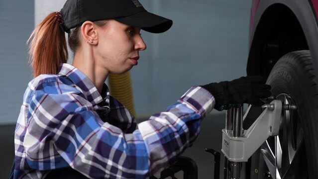 A female auto mechanic makes a camber. Woman working in a car service.