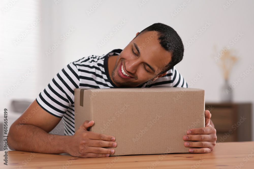 Wall mural happy young man with parcel at table indoors. internet shopping