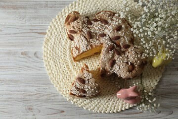 Delicious Italian Easter dove cake (traditional Colomba di Pasqua) and festive decor on white wooden table, top view. Space for text