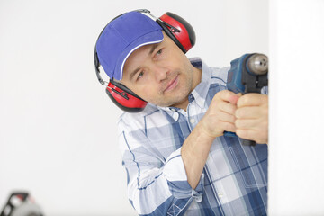 builder wearing protective workwear and holding electric drill