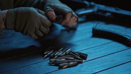 The male hands of a Ukrainian military man load a kalashnikov assault rifle magazine with...