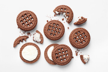 Tasty chocolate sandwich cookies with cream on white background, flat lay