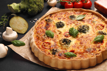 Delicious homemade vegetable quiche and different vegetables on black table