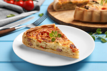 Piece of delicious homemade vegetable quiche on light blue table, closeup
