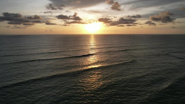 Sunset scene drone footage over orange sky on the horizon reflecting on the sea