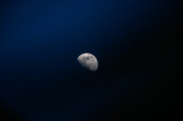 Fototapeta premium Beautiful view of the moon in a waxing gibbous phase appearing in the dark blue sky