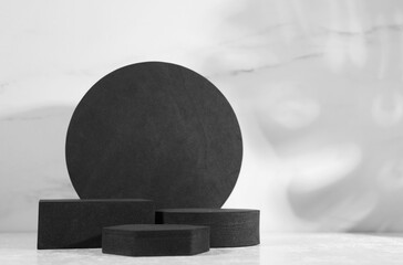 Black geometric figures on white table, space for text. Stylish presentation for product