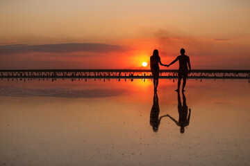 Valentines day. Heterosexual couple in love, silhouette of romantic young man and woman holding hands enjoying sea sunset on beach during travel holidays vacation, getaway, honeymoon, dating.