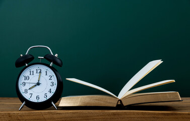 Alarm clock and book in front of the blackboard