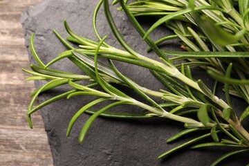 Fresh green rosemary with slate plate on table, closeup