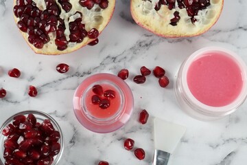 Flat lay composition with homemade cosmetic products and fresh pomegranate on white marble table. DIY beauty recipe
