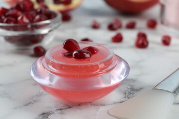 Cosmetic product made of pomegranate on white marble table, closeup. DIY beauty recipe