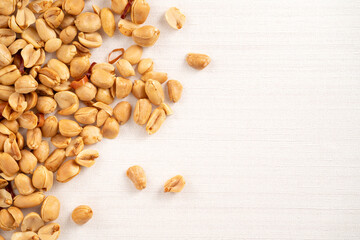 Spicy flavored peanut kernel spilling on white table background.