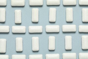 Tasty white chewing gums on light blue background, flat lay