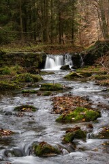 Long exposure shot of the cascade waterfall surrounded by the mossy rocks in the forest