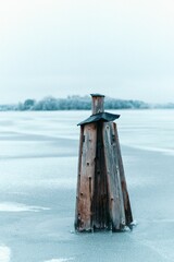 Fototapeta premium Vertical shot of a wooden post stuck in the ice