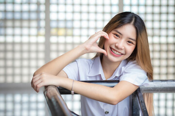 Beautiful young Asian student girl wearing a Thai university uniform and teething retainer stands...