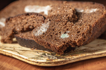 Dry musty bread. Spoiled, non-consumable food. Slices of black bread, covered with mold. Mold on bread