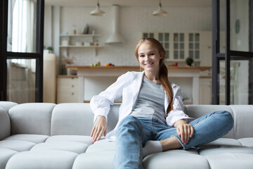 Young beautiful woman in casual clothes relax on the sofa in the living room smiling looking at the camera