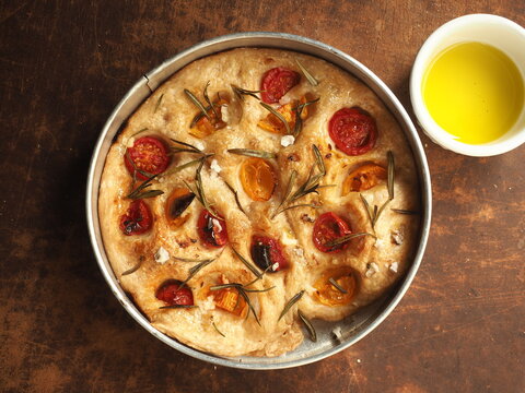 baked round Focaccia with rosemary, red and yellow tomato, sea salt and olive oil