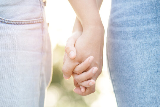 Couple lovers romantic holding hands towards with bright sun flare in public parks, or close up view in a conceptual image first love adolescent young relationship. lover