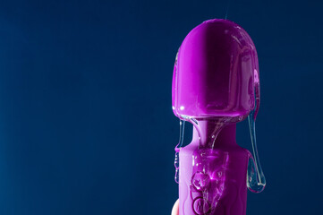 Intimate lubricant pours on a purple vibrator on a blue background. Copy space. 