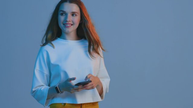 Young girl chatting in social network, answering message on the go while walking, using mobile phone apps. Copy space
