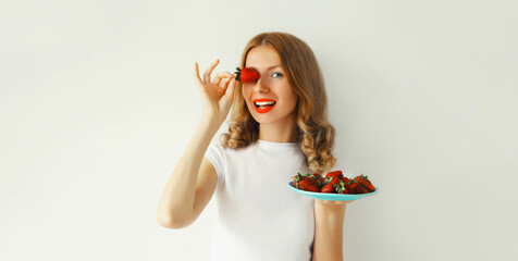 Portrait of happy smiling woman holding plate with fresh strawberries on white background