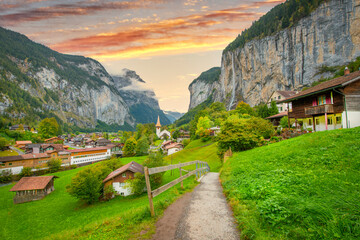 Amazing autumn landscape of touristic alpine village Lauterbrunnen with famous church and Staubbach...