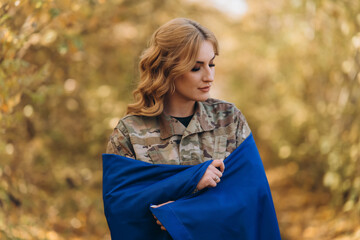 Naklejka premium A Ukrainian military woman with a Ukrainian flag.