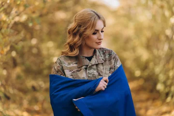 Foto op Canvas A Ukrainian military woman with a Ukrainian flag. © Vitaliy