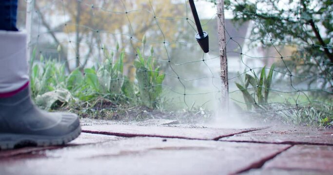 Low angle shot of working with a high pressure water tool cleaning some old flagstones.