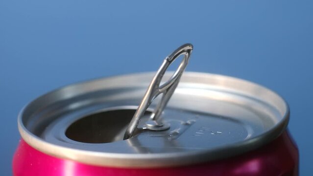 Opening soda or beer can macro close up of can pull tab, hand open lemonade, refreshment. High quality 4k footage. With my fingers I open a red tin can with a drink in the blue background close-up