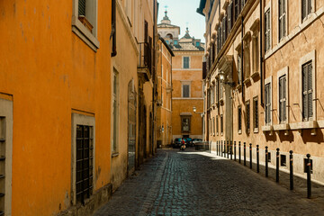 A narrow street with a yellow building in Rome