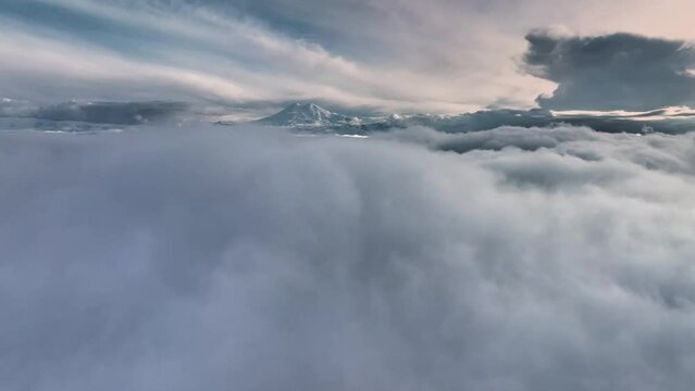 Aerial view low flying above the clouds at sunset. Sleeping volcano Elbrus in the Caucasus in the sunset rays. cloud surfing