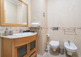 Naklejka na ściany i meble White urinal in the bathroom with a washbasin and towels in a modern apartment.