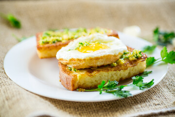 Fried croutons in batter with garlic and herbs and a fried egg in a plate.