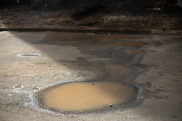 Puddle in sun. Dirty water. Puddle in road.
