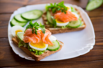 fried toast with lettuce, egg, cucumbers and red fish in a plate.