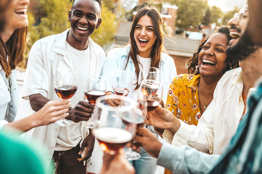 Multiracial friends celebrating rooftop party drinking red wine together - Cheerful young people enjoying barbeque diner in restaurant terrace - Happy teenagers enjoying happy hour at winery bar