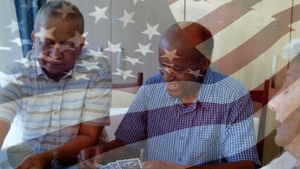 Animation of waving flag of america over senior diverse friends playing cards at home - Powered by Adobe